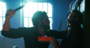 Frank Castle (the Punisher) charges towards Matt Murdock (Daredevil) while holding a weapon. The two men are in Frank's secret hideout, and are dramatically backlit by windows in the background.